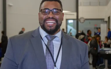 alumni Dante Willams standing in front of a NHCC career fair