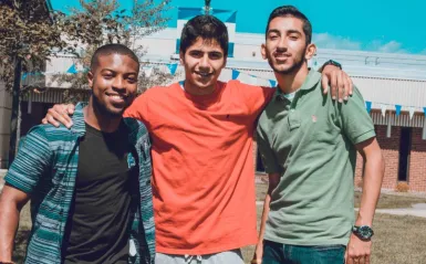 three male students smiling outside