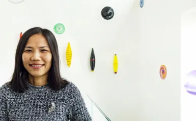 computer science student standing inside art decorated hallway smiling at the camera