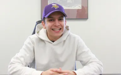 student Armando Morales sitting at a table smiling