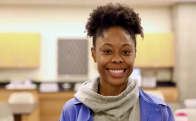 Phlebotomy student Tiahna James standing inside NHCC classroom smiling and facing the camera