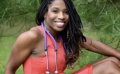 nursing alumni Jeanette Rupert posing for the camera outside below a pine tree