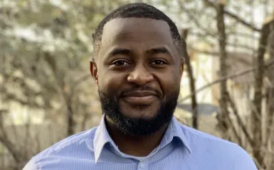 STEM alumni Alain Njipwo outside smiling at camera