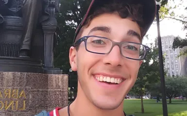 nursing alumni Wyatt Smith standing outside in font of a statue 