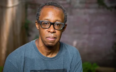 man wearing glasses with a brick background 