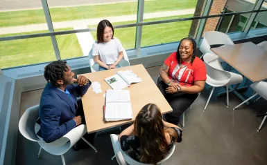 photo of four students studying at a hallway table