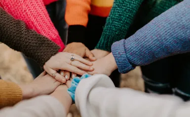 group of people standing in circle with their hands in the center