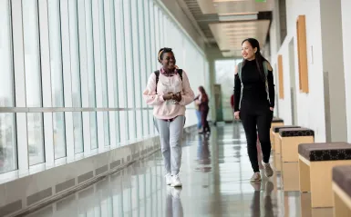 a photo of two NHCC alumni students walking in the hall 