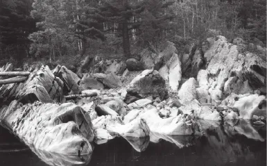 a black and white photograph of rocks by the water at Jay Cooke State Park