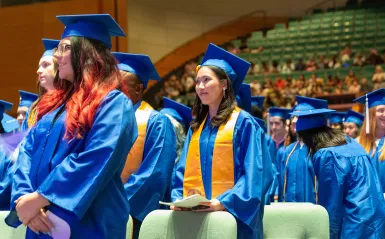 students wearing caps and gowns in the commencement hall