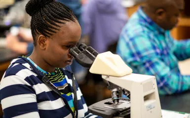 a photo of a student looking through a microscope