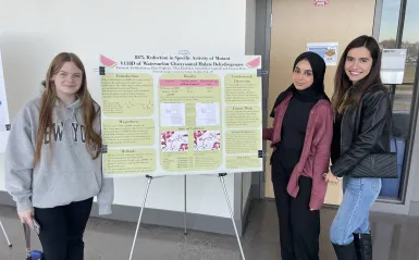 a photo of biology students next to their poster presentation