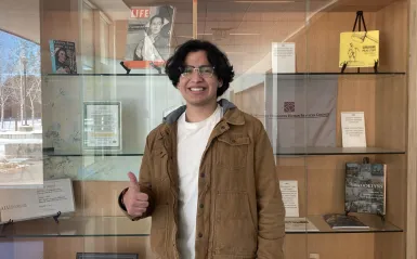 student smiling in front of bookcase