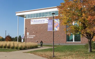 student walking into campus building in the fall 