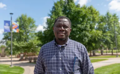 a photo of an adult male student, smiling in the courtyard