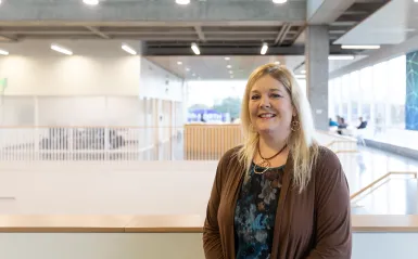 woman smiling with large atrium behind her 