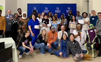 This is a group photo of various students and staff who attended the Student Life Awards Banquet. The group piled together for a photo in front of the NHCC logo backdrop. 