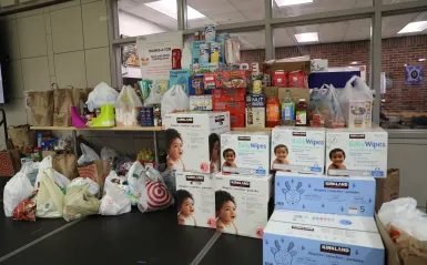 this is a photo of a pile of assorted perishable and nonperishable donations on the stage in the Campus Center during an annual Food Drive event. 