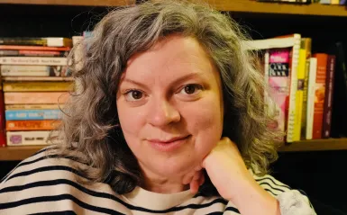 this is a headshot photo of NHCC faculty, Kelly Lundquist taken in front of a bookcase. 