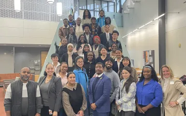 large group of students and staff standing on stairs in large room smiling. 