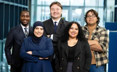 this is a photo of the five, spring 2026 Kappa Beta Delta Officers, Exocee, Noah, Juan, Muna and Norma all smiling and facing the camera for a photo. 