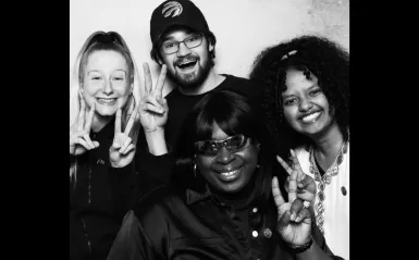 this is a black and white photobooth photo of four NHCC students smiling for the camera. 