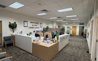 this is a photo of the CARE Center Office with administrative assistant, male NHCC employee, Kory sitting at the desk, looking at his computer. 