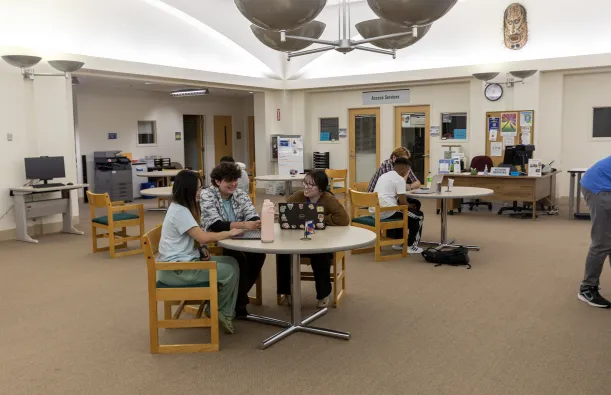 students working at a table with a tutor