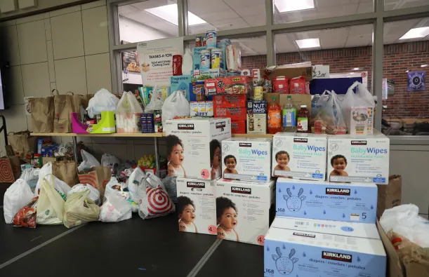 this is a photo of a pile of assorted perishable and nonperishable donations on the stage in the Campus Center during an annual Food Drive event. 