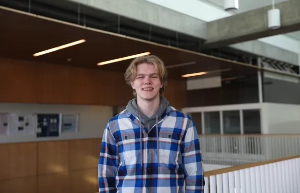 this is a photo of former NHCC student, Casey Hjelmstad, standing near the top of the staircase in NHCC's BHCC building, smiling at the camera. 