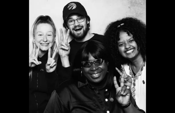 this is a black and white photobooth photo of four NHCC students smiling for the camera. 
