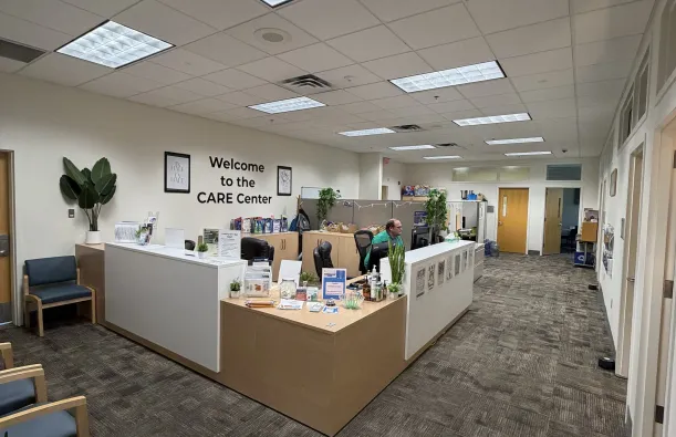 this is a photo of the CARE Center Office with administrative assistant, male NHCC employee, Kory sitting at the desk, looking at his computer. 
