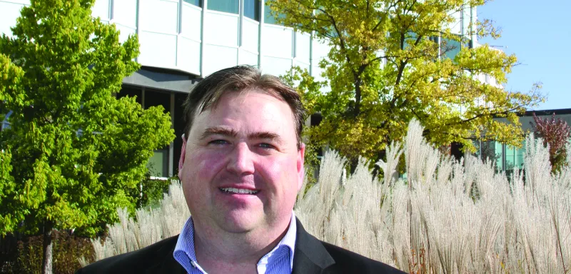 Man standing outside large building in a suit smiling 