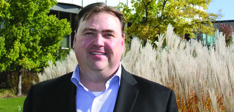 Man standing outside large building in a suit smiling 