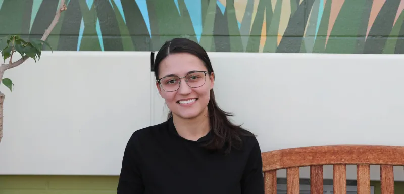 student sitting on a bench smiling