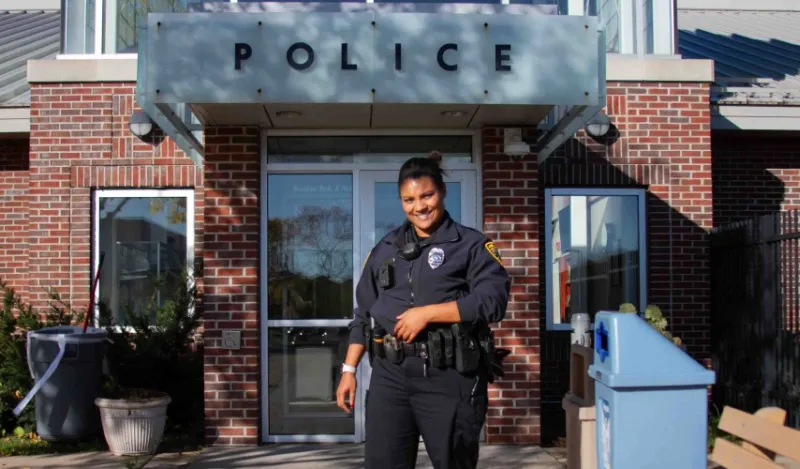 female alumni cop standing outside police station