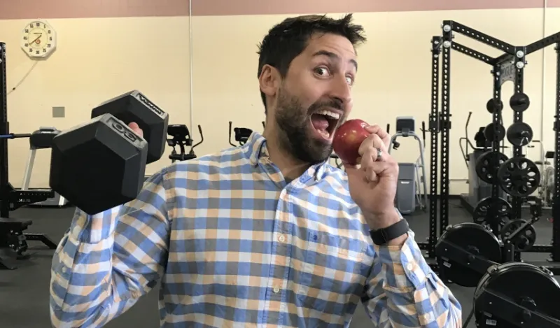 faculty member lifting a weight and eating an apple 