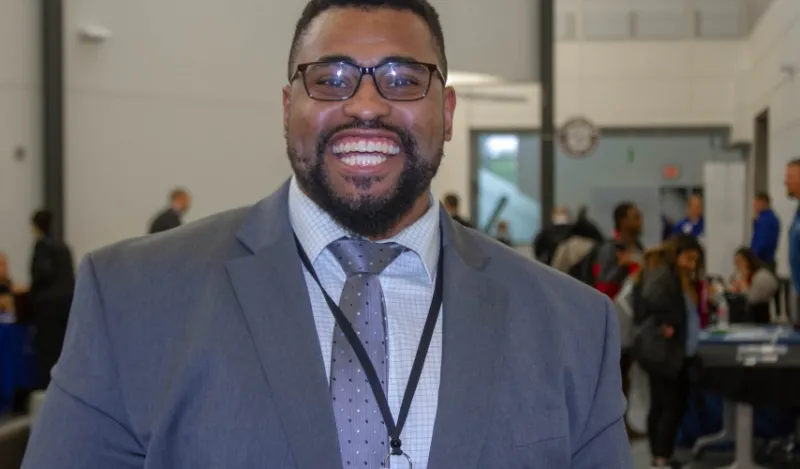 alumni Dante Willams standing in front of a NHCC career fair