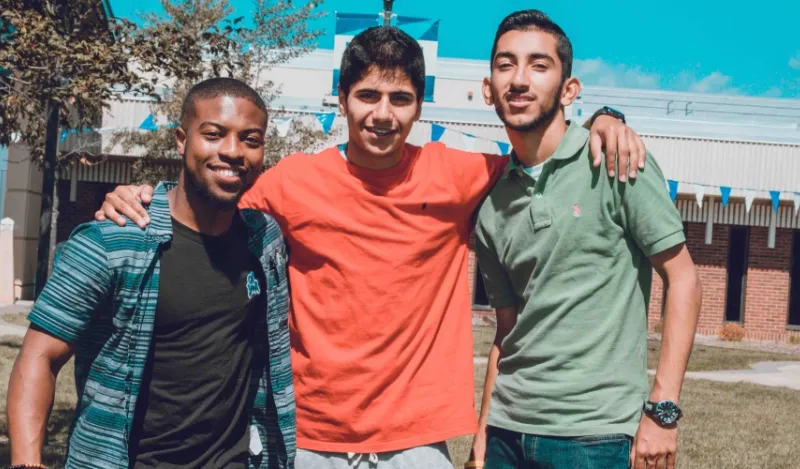 three male students smiling outside