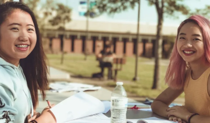 two female students sitting outside working on homework