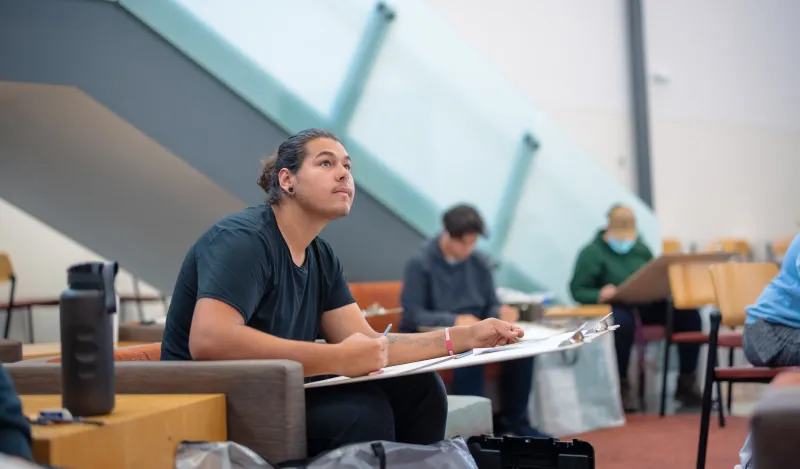 Students will large drawing boards drawing in a lounge 