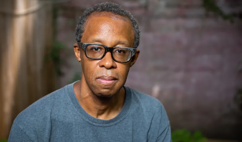 man wearing glasses with a brick background 