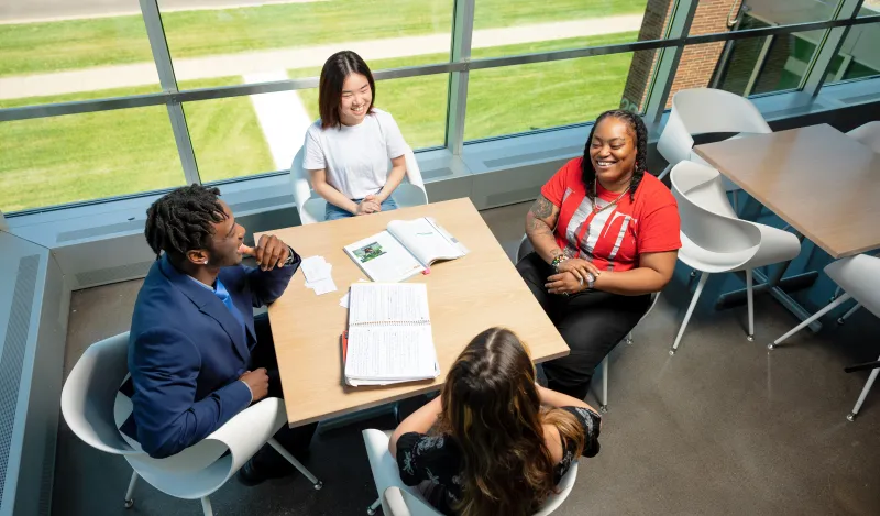 photo of four students studying at a hallway table