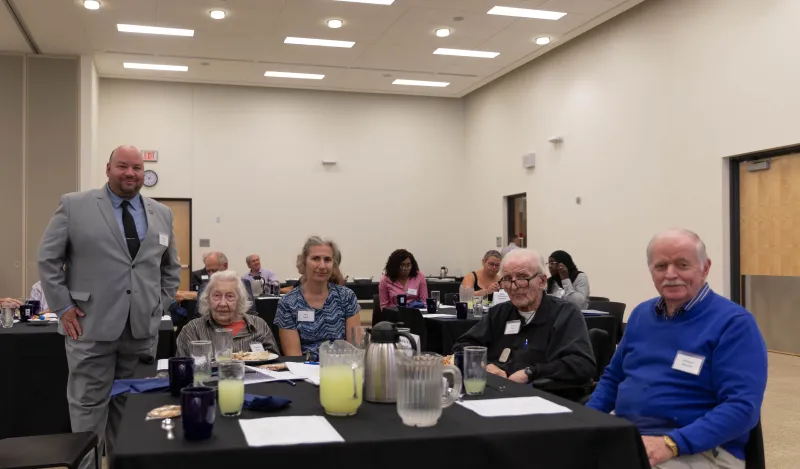 a photo of Rolando and retirees at luncheon