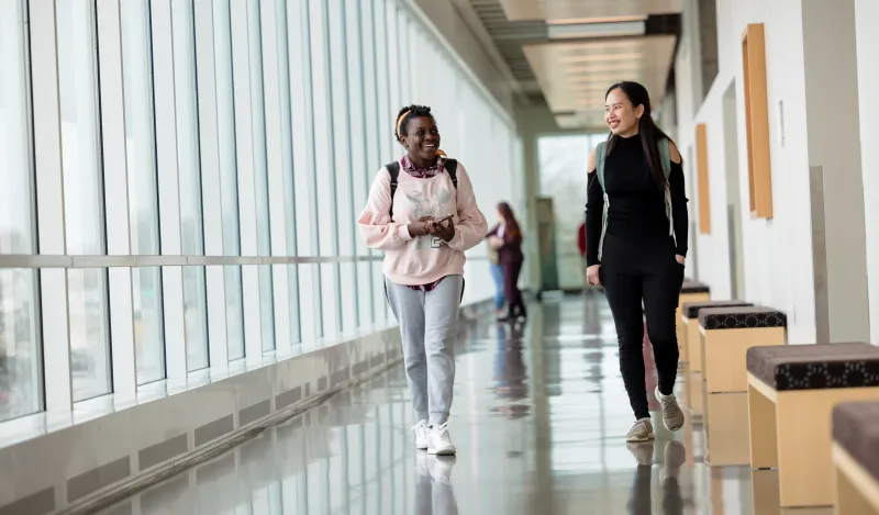 a photo of two NHCC alumni students walking in the hall 