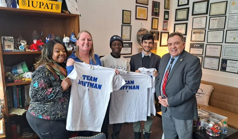 students holding t-shirts in a senator's office