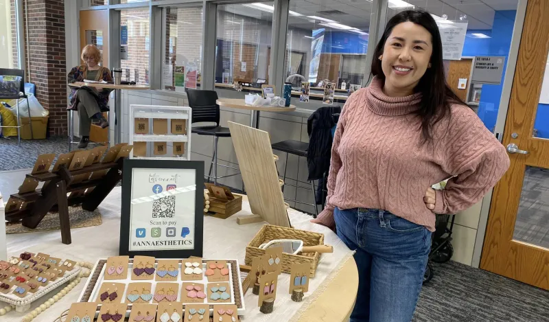 a photo of a woman selling earrings at our makers market