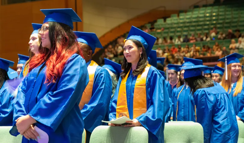 students wearing caps and gowns in the commencement hall