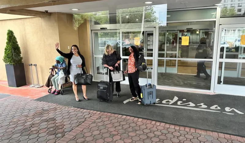 A photo from Donald Agik's study abroad trip, staff waving goodbye outside of a hotel lobby