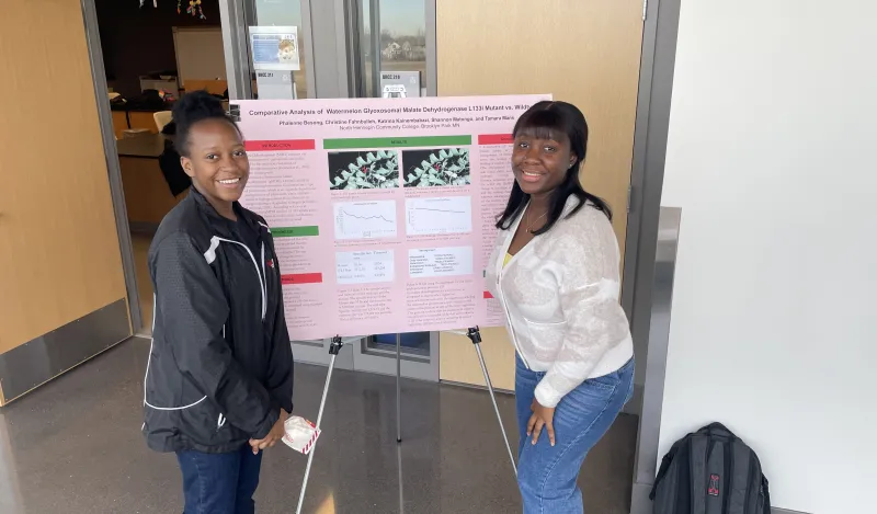 a photo of biology students next to their poster presentation